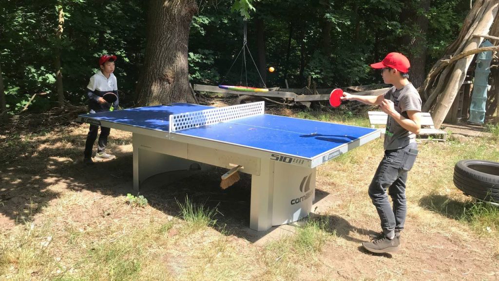 Zwei Kinder spielen auf einer fest installierten Tischtennisplatte